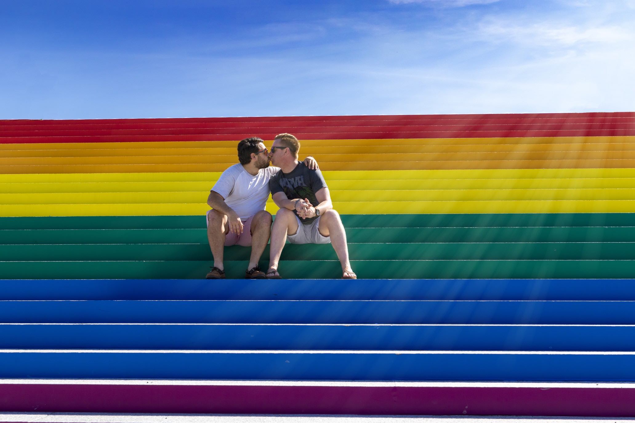 Two men kissing on rainbow flag steps