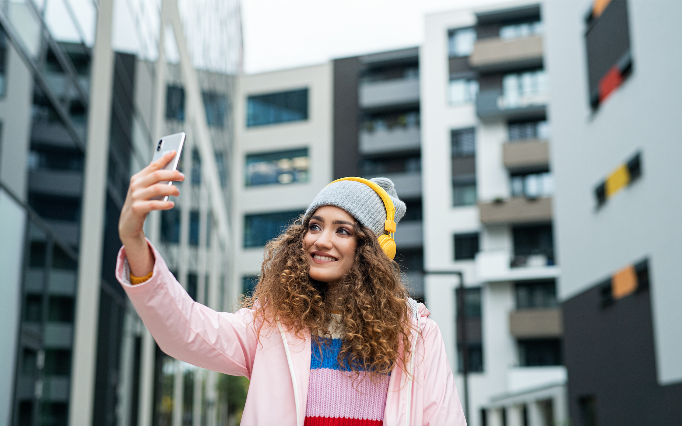 Young woman with smartphone making video for social media outdoors on street. by halfpoint