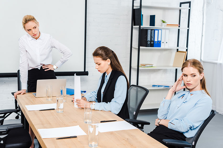 angry lady boss talking to depressed female employees at modern office