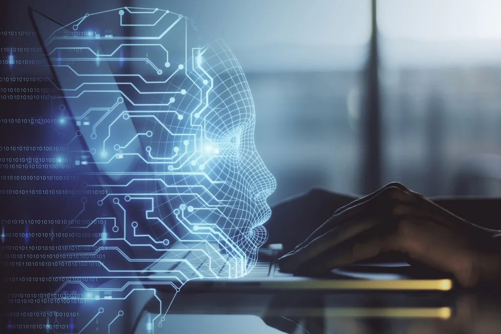 A glowing, wireframe digital human head overlaid with circuit patterns, representing AI, with hands typing on a laptop keyboard in the blurred background. Binary code is subtly visible.