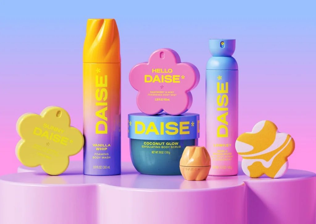 A collection of seven colorful Daise body care products, including body wash, scrub, and fragrance mists, displayed on a pink platform against a gradient background.